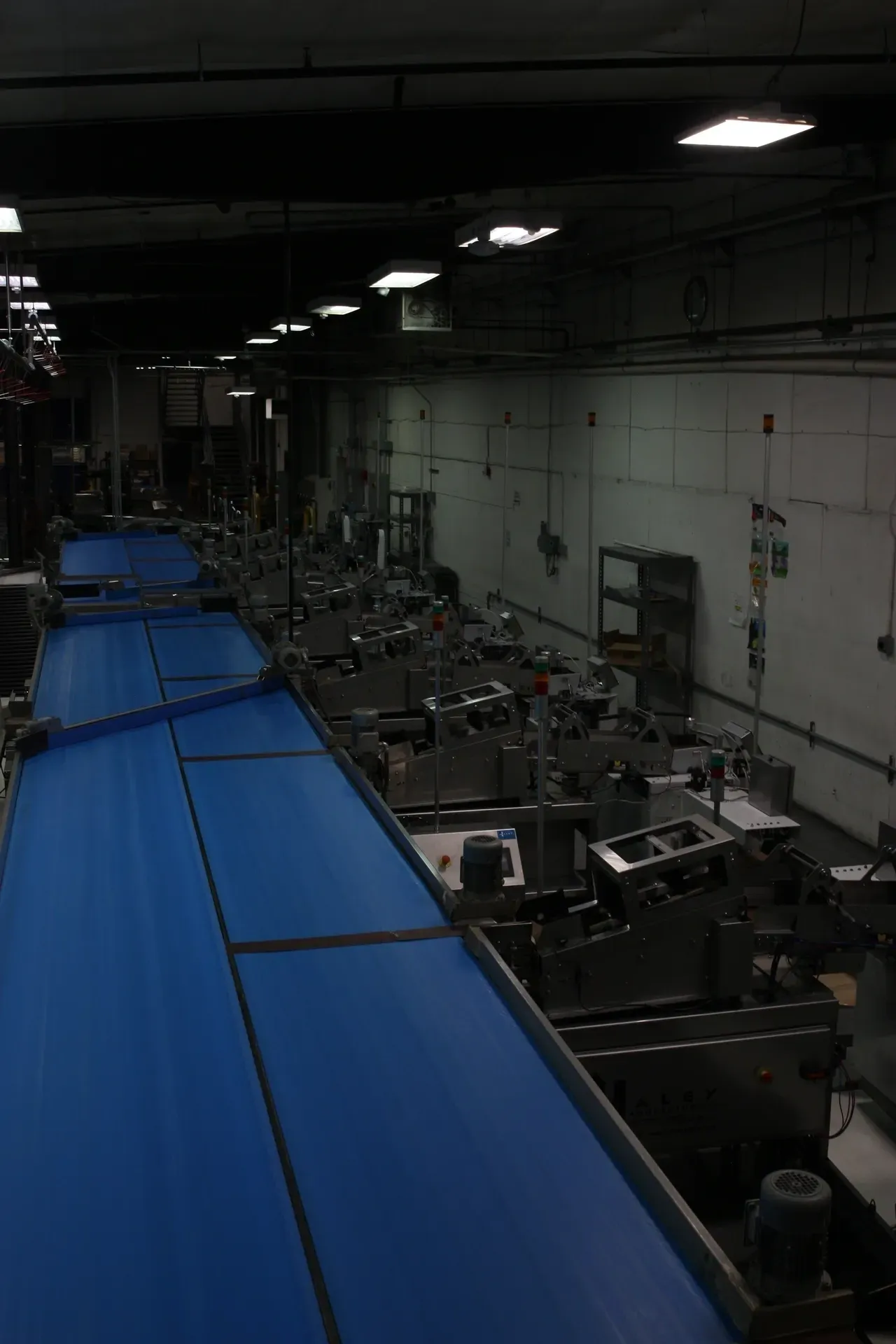 A conveyor belt in a warehouse filled with machines.