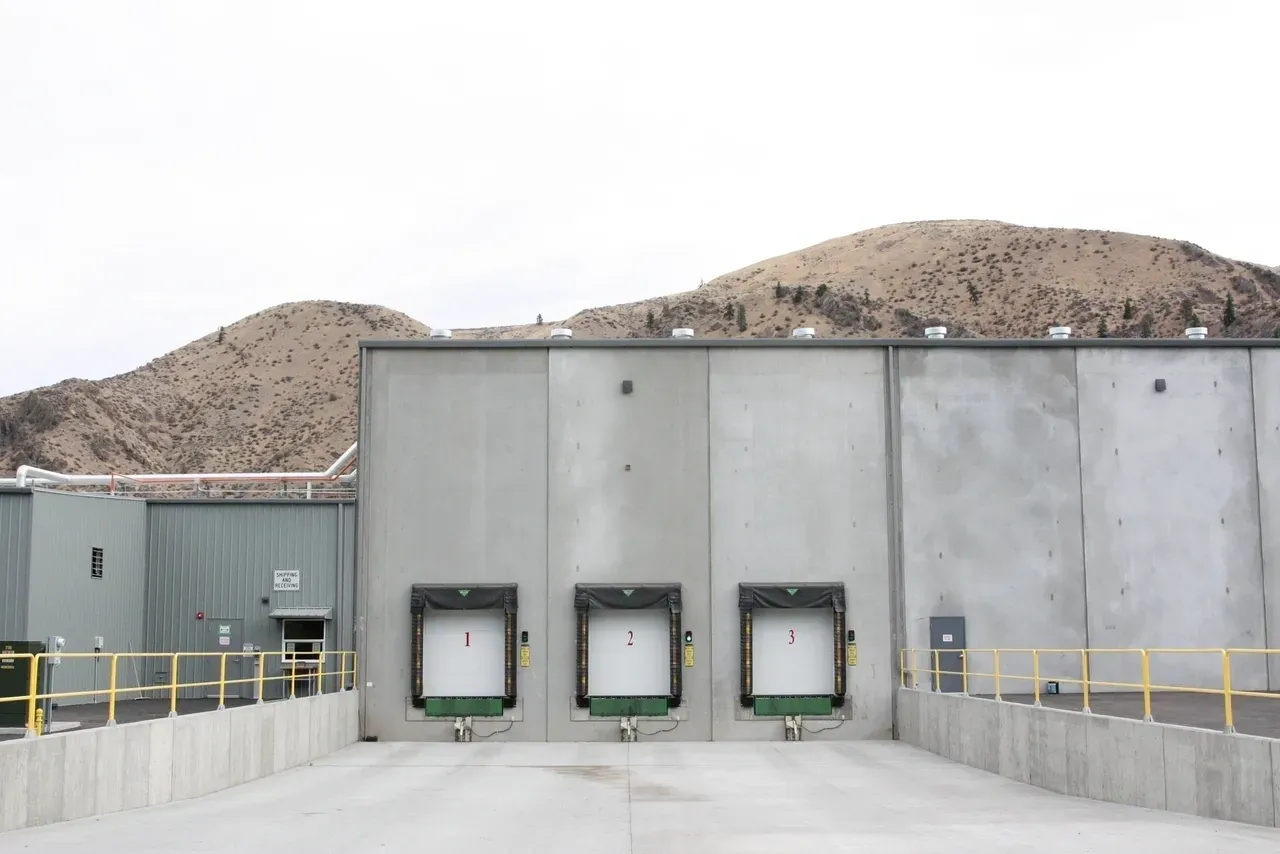 Three large doors on a building with mountains in the background.